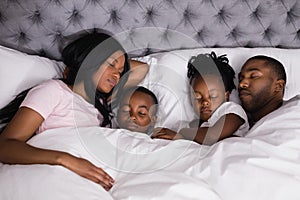 High angle view of family sleeping together on bed