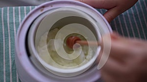 High-angle view of female artisan craftperson mixing melted wax in pot to make candles, slow motion. Process of making