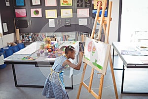 High angle view of focused girl painting on canvas