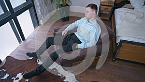 High angle view focused young businessman sitting in armchair thinking. Wide shot portrait of concentrated confident