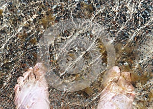 High angle view of foots standing in the sea