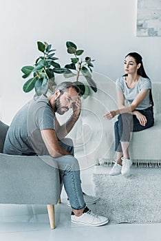 high angle view of frustrated partners sitting on armchair and couch relationship photo