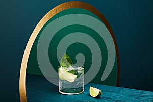 High angle view of glass with refreshing drink with lime, ice cubes and mint leaf on wooden surface