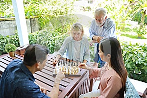 High angle view of a group of multiethnic senior people playing chess board with happy smiling face on holiday vacation