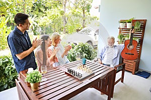 High angle view of a group of multiethnic senior people playing guitar and sing a song after playing chess board with happy