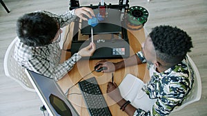 High angle view of guys making 3d model with printer using computer in office