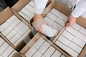 High-angle view of hands of worker putting packed products in ca