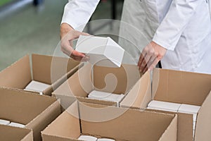 High-angle view of hands of worker putting packed products in ca