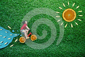 High Angle View of a Happy Asian Kids. Girl on Bicycle Lay Down at Green lawn in Summer Sunny Day. Imagination and Creativity