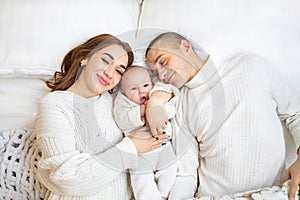 High angle view of happy family with newborn baby lying on bed at home.