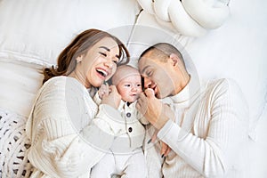 High angle view of happy family with newborn baby lying on bed at home.