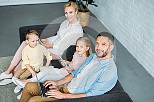 high angle view of happy family using digital devices and smiling