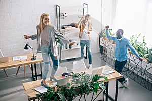 high angle view of happy multiethnic business colleagues dancing and having fun in modern