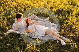 High-angle view of happy young couple relaxing in nature park lying together on beautiful field of green grass in sunset