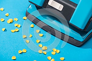 High angle view of holepunch with paper circles on blue background.