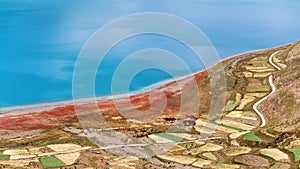 High angle view of holy Yamdrok Lake and colorful farm land, amazing blue water surface with little ripples