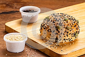 High angle view of homemade burger bun sprinkled with white and black sesame and pumpkin seeds