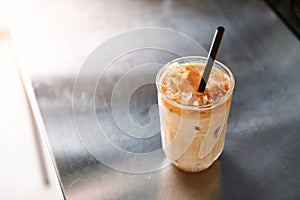 High angle view of an iced coffee latte with straw on a steel counter top in coffee house