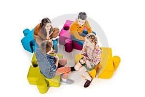 High Angle View of kids sitting on jigsaw puzzle poufs and talking Isolated On White. photo