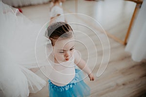 High angle view of little girl with down syndrome at ballet class in dance studio. Concept of integration and education