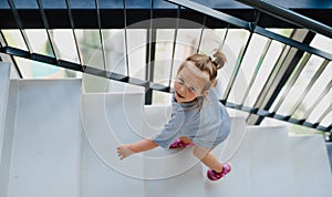 High angle view of little girl walking up the stairs indoors.