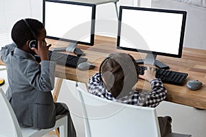 High angle view of male colleagues talking through headset at desk