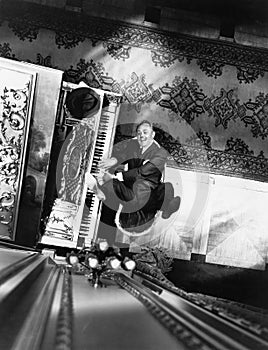 High angle view of a man reclining on a chair and playing a piano