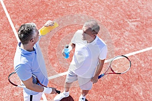 High angle view of men talking while standing on tennis court during match