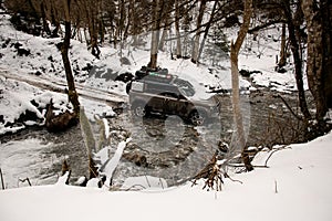 high angle view on off-road vehicle driving through a mountain river at winter