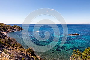 High angle view over Ogliera beach, a little wild free beach with dark sand, rocks and stones near Pomonte