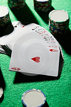 High angle view of pack of cards with casino chips on green background