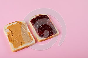 High angle view of peanut butter and preserves on bread slices over pink background