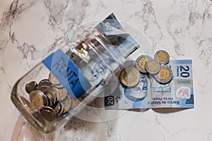 High angle view of pesos and coins in a jar with a blue [Renta-Rent] sticker on it on the table photo