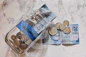 High angle view of pesos and coins in a jar with a blue [vacaciones - vacations] sticker on it photo
