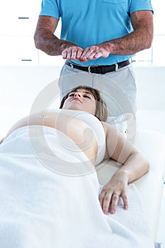 High angle view of pregnant woman relaxing while male therapist performing reik