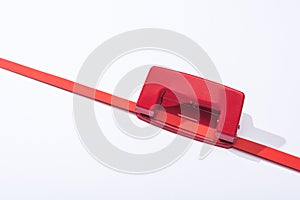 High angle view of red holepunch and paper strip on white background.