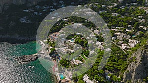 High angle view of residencies and guesthouses on slope rising from sea coast. Travel destination on sunny day. Capri