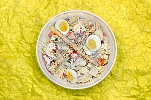 High-angle view of a salad with pasta, eggs, vegetables adn breadsticks