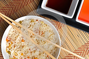 High angle view of sauces and a bowl of cooked rice with vegetables on the table