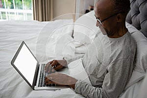 High angle view of senior man using laptop on bed