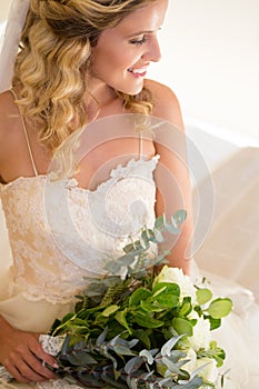 High angle view of smiling bride holding bouquet while sitting on bed