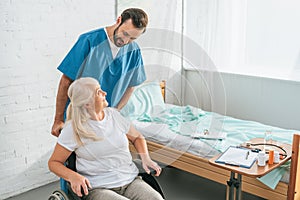 high angle view of smiling male nurse looking at senior woman