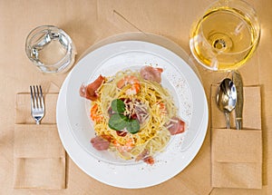 High angle view of spaghetti pasta in white plate near glass wit