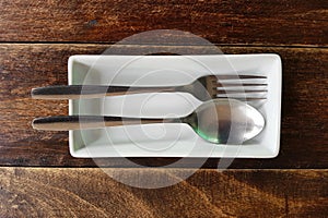 High angle view of spoon and fork on plate on wooden table