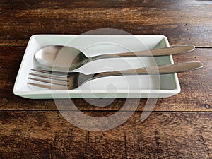 High angle view of spoon and fork on plate on wooden table