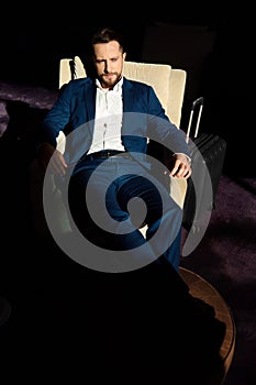 High angle view of a successful young businessman at business trip, relaxing on an armchair with outstretched crossed legs on an