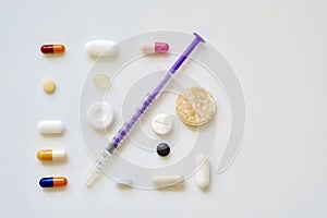 High angle view of a syringe needle and various pills on the table under the lights