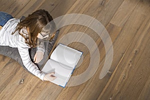 High angle view of teenage girl reading book on floor at home