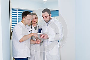 High angle view of three doctors in white coats having conversation at hospital hall