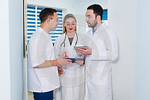 High angle view of three doctors in white coats having conversation at hospital hall